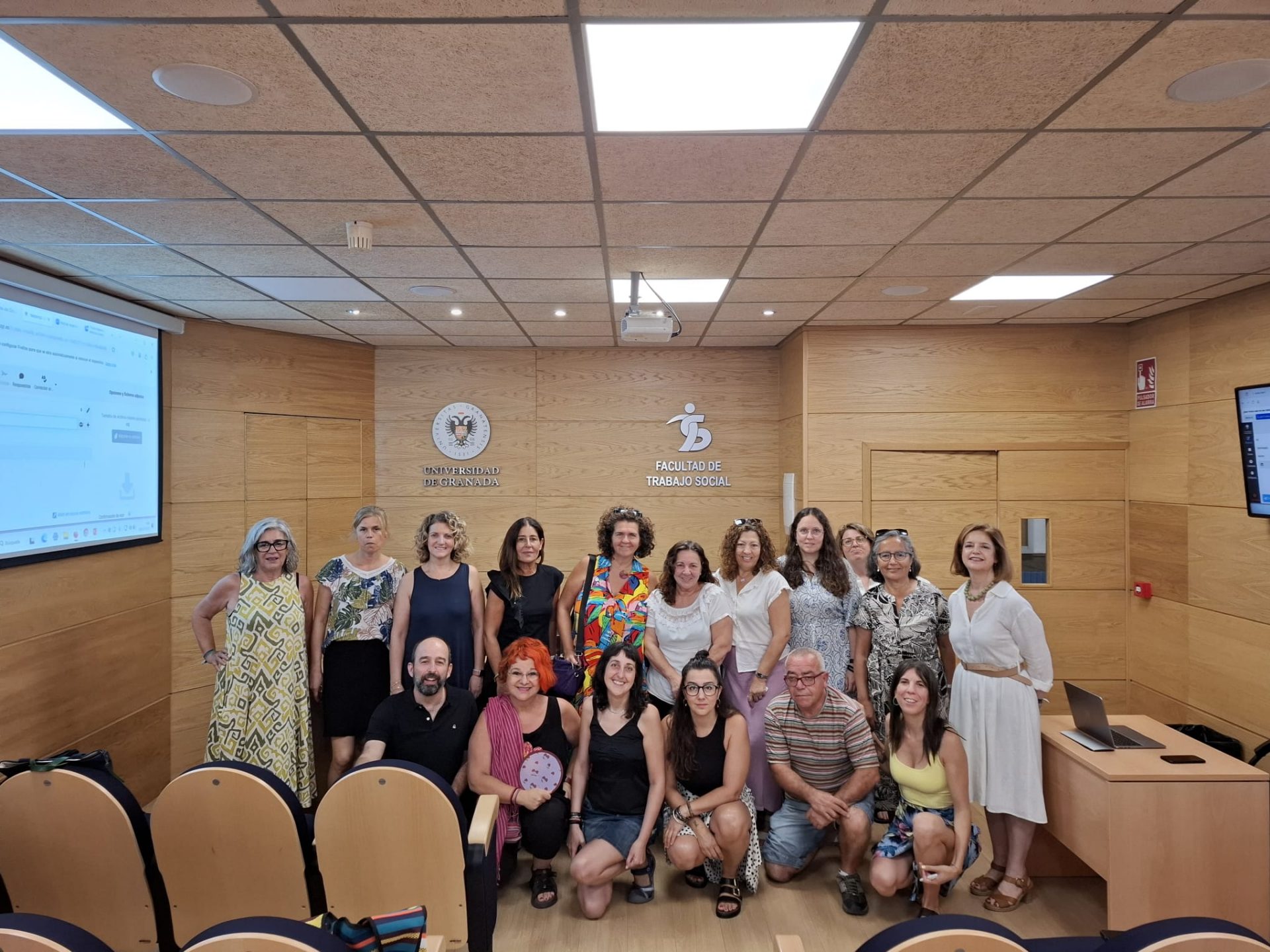 Aparece una imagen con un grupo de gente reunida en la sala de trabajo social de la UGR