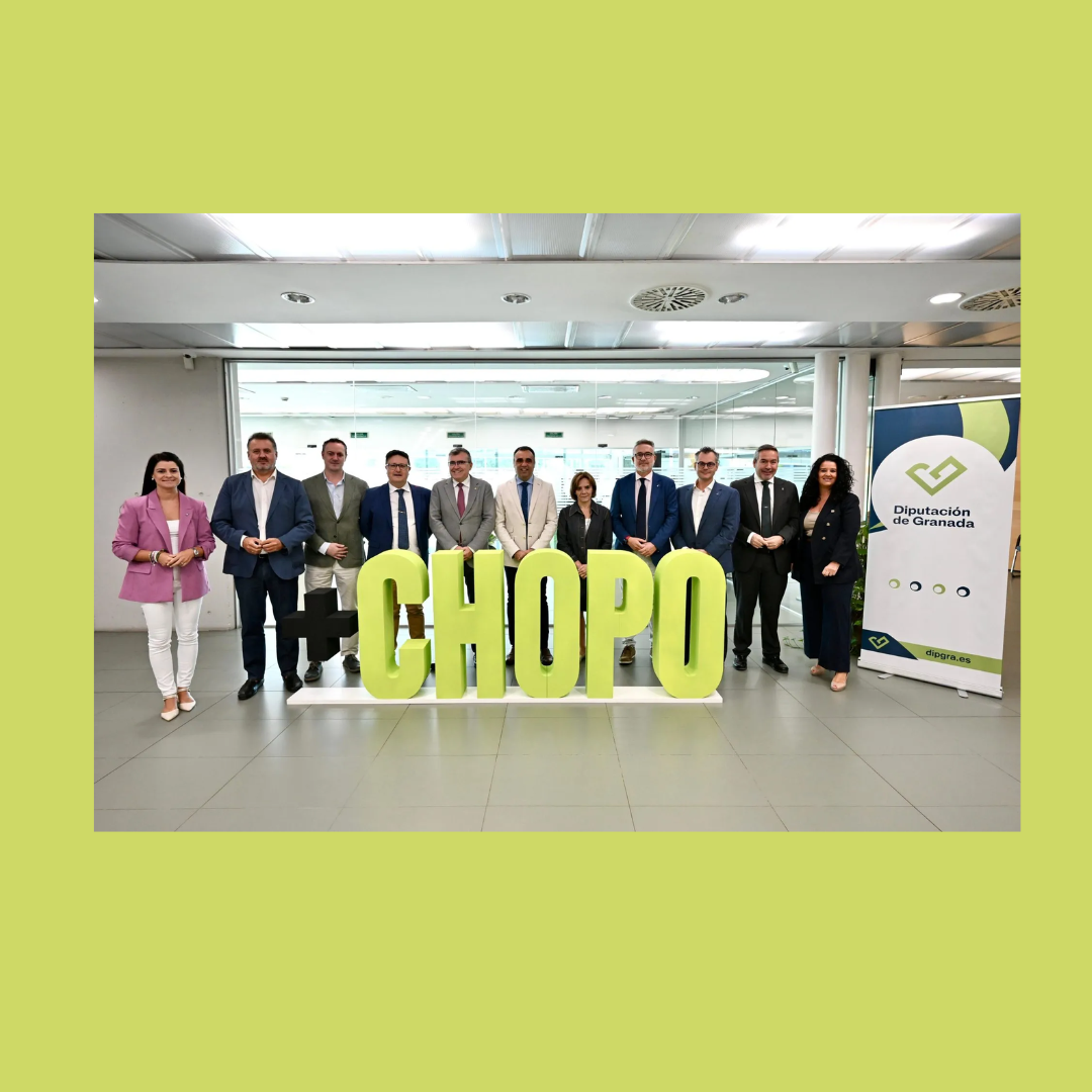 Aparece una imagen que muestra una presentación institucional del proyecto “+CHOPO” impulsado por la Diputación de Granada. En el centro se destacan letras corpóreas color verde lima, acompañadas de autoridades y técnicos. El fondo neutro y los trajes formales refuerzan el carácter oficial del evento.
