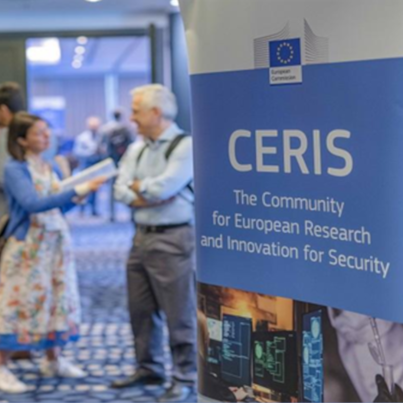 Cartel | Jornada (Bruselas) | CERIS: Lucha contra el crimen y el terrorismo | 24 y 25 septiembre 2024 Aparece una imagen en la que se puede observar a un hombre y una mujer hablando en un pasillo, apareciendo el cartel con el logo del CERIS